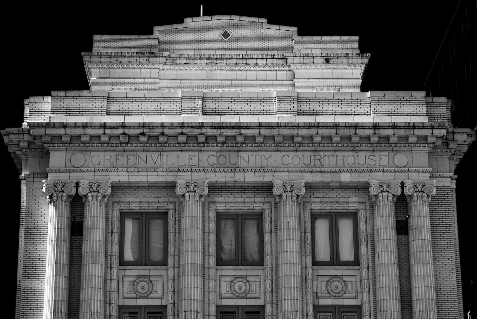 The stone facade of a classical building with columns and tall windows
